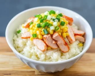 A bowl filled with rice, chicken, and street corn, ready to serve.
