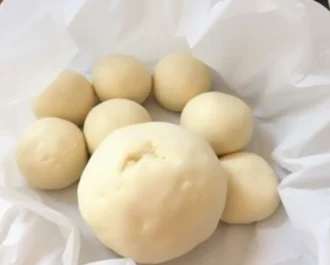 Soft and golden Hawaiian dinner rolls arranged on a plate.